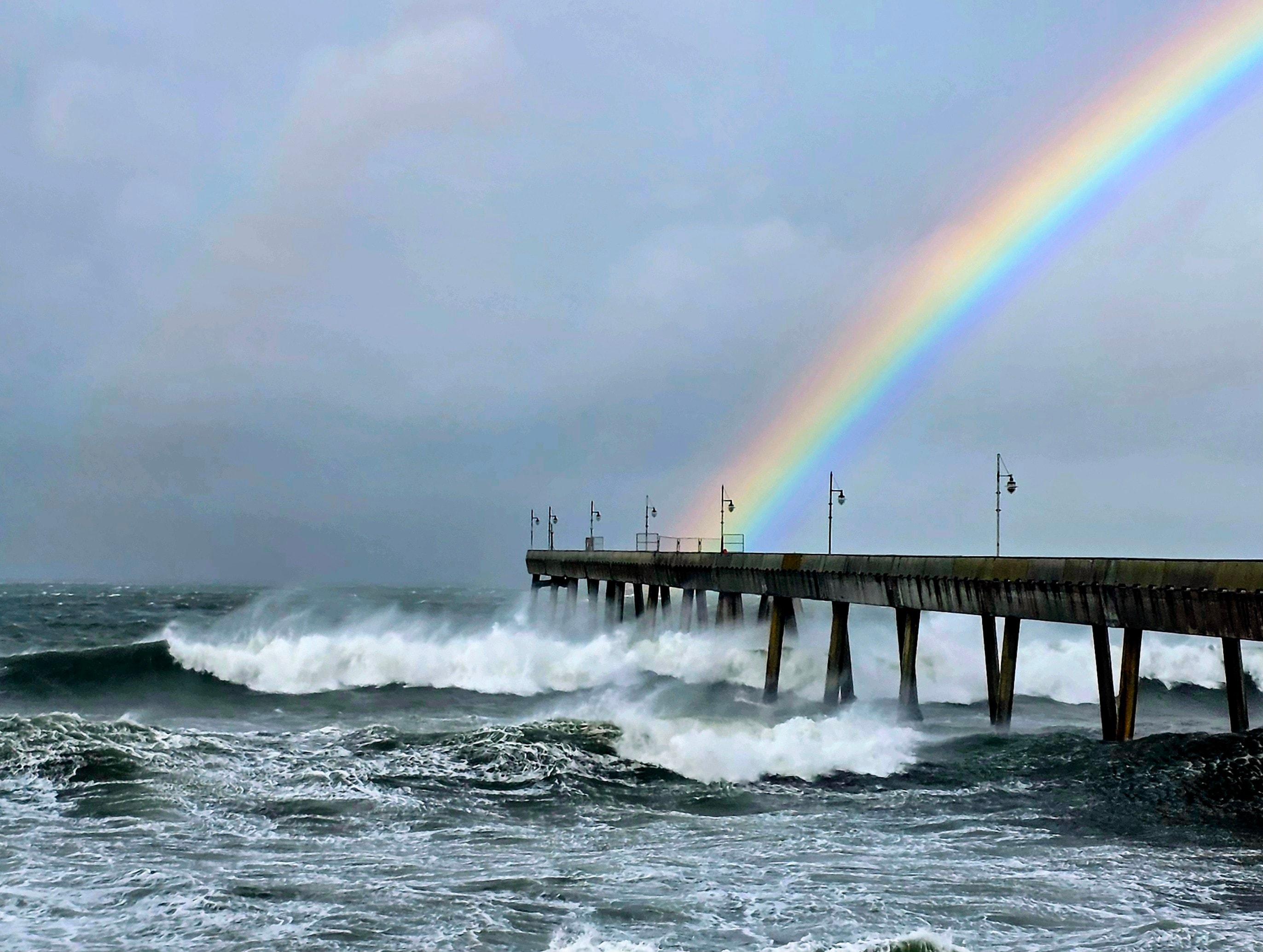 Rainbow appearing over storm waves at the Pacifica Pier